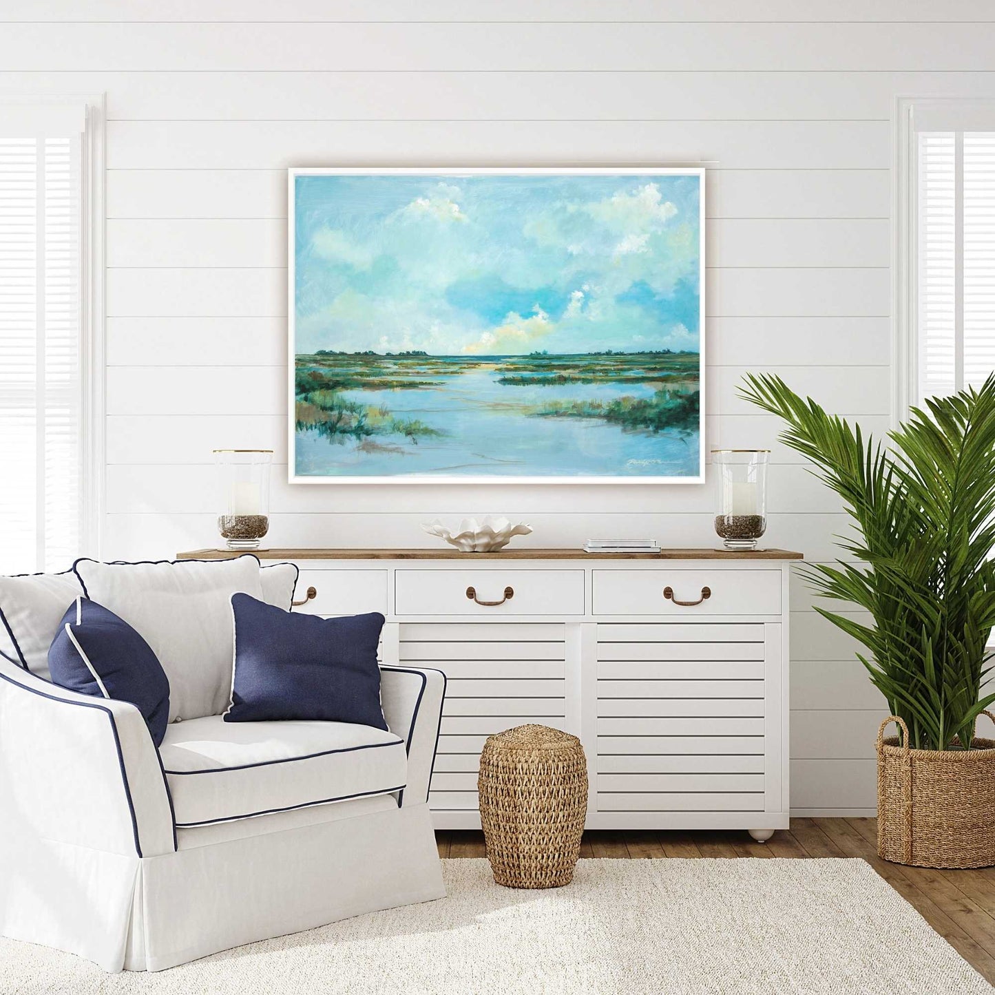Living room with white sofa, decorative pillows, and a large painting of a coastal landscape by Patrick Reid O'Brien on the wall.