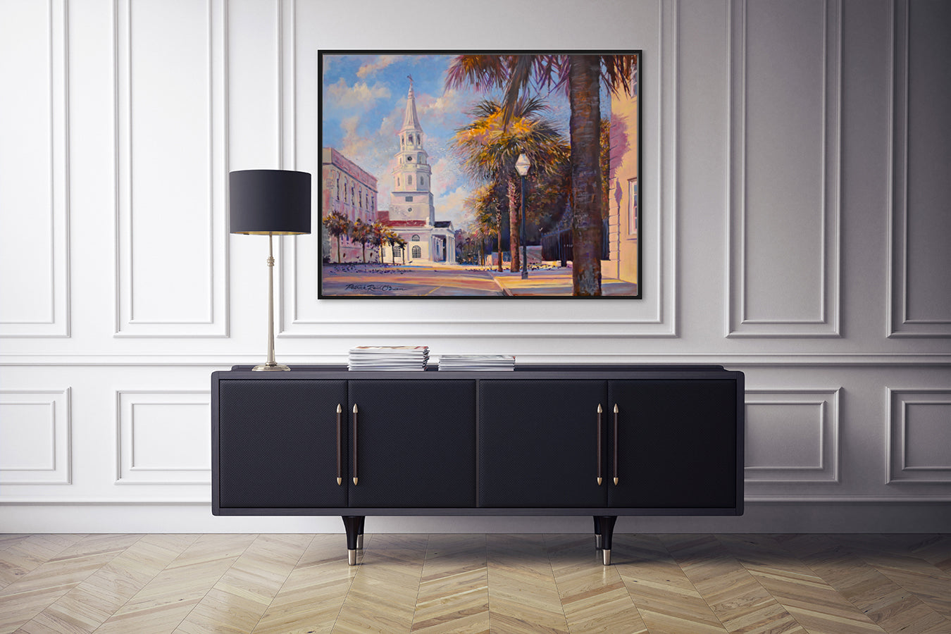 A painting titled 'The Early Birds' by Patrick Reid O'Brien displayed on a wall over a black sideboard, depicting a vibrant charleston street scene with birds.