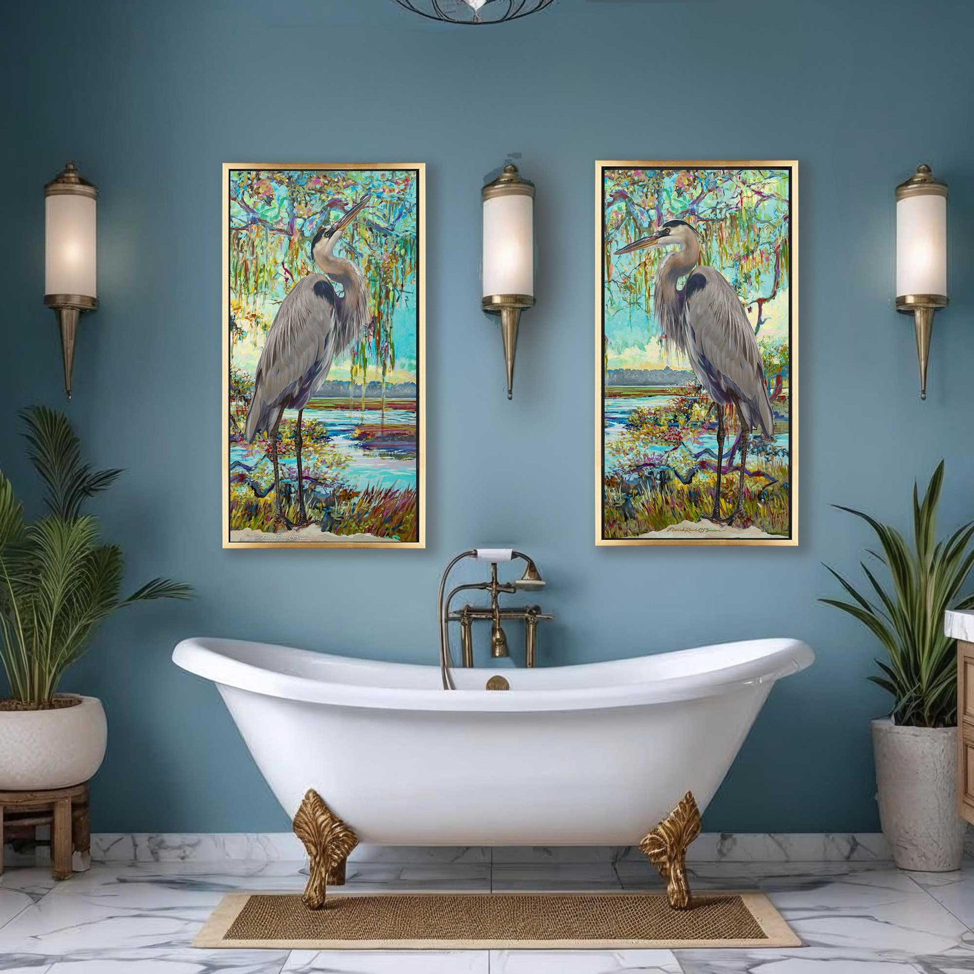 Bathroom with a white freestanding bathtub, gold feet, and two framed artworks of herons on a blue wall.