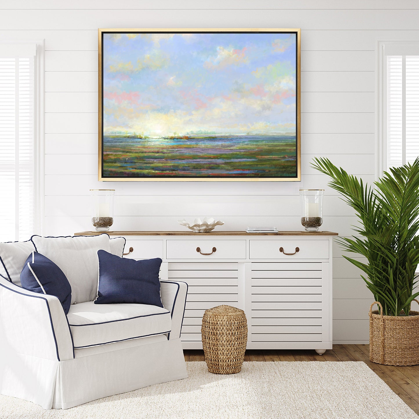 Living room with a white armchair, decorative pillows, a sideboard, and a large painting of a landscape.