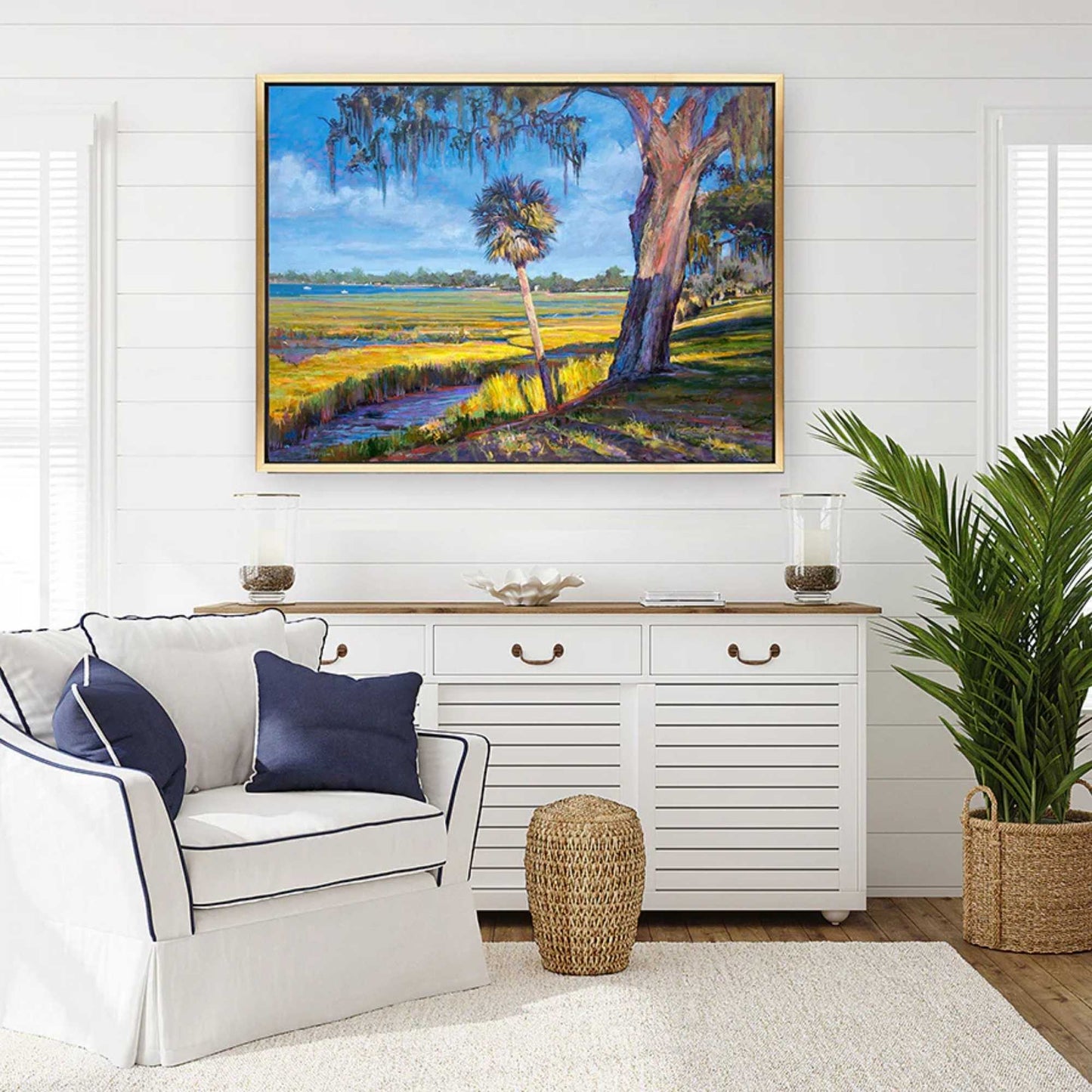 Living room with a coastal landscape by Patrick Reid O'Brien on the wall, white sofa, and decorative items.
