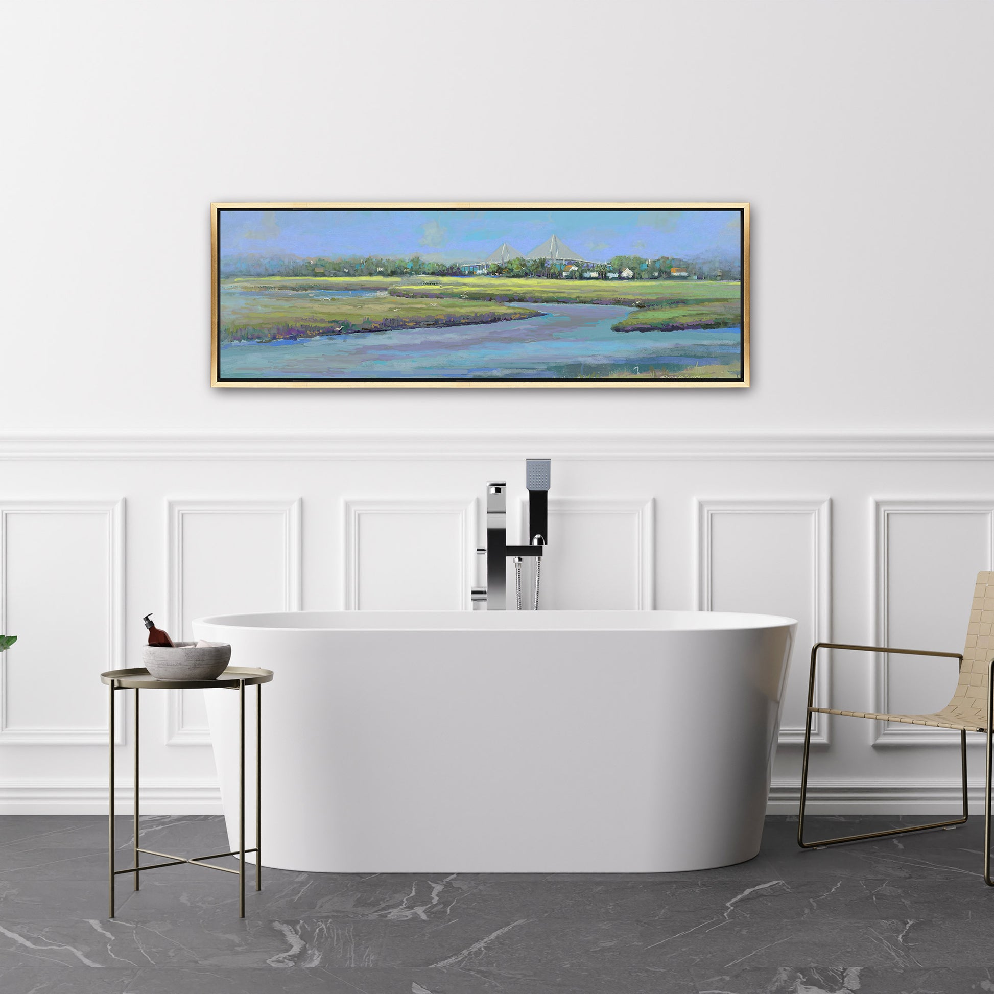 Modern bathroom with a freestanding bathtub, side table, and chair, featuring a large framed landscape painting on the wall.