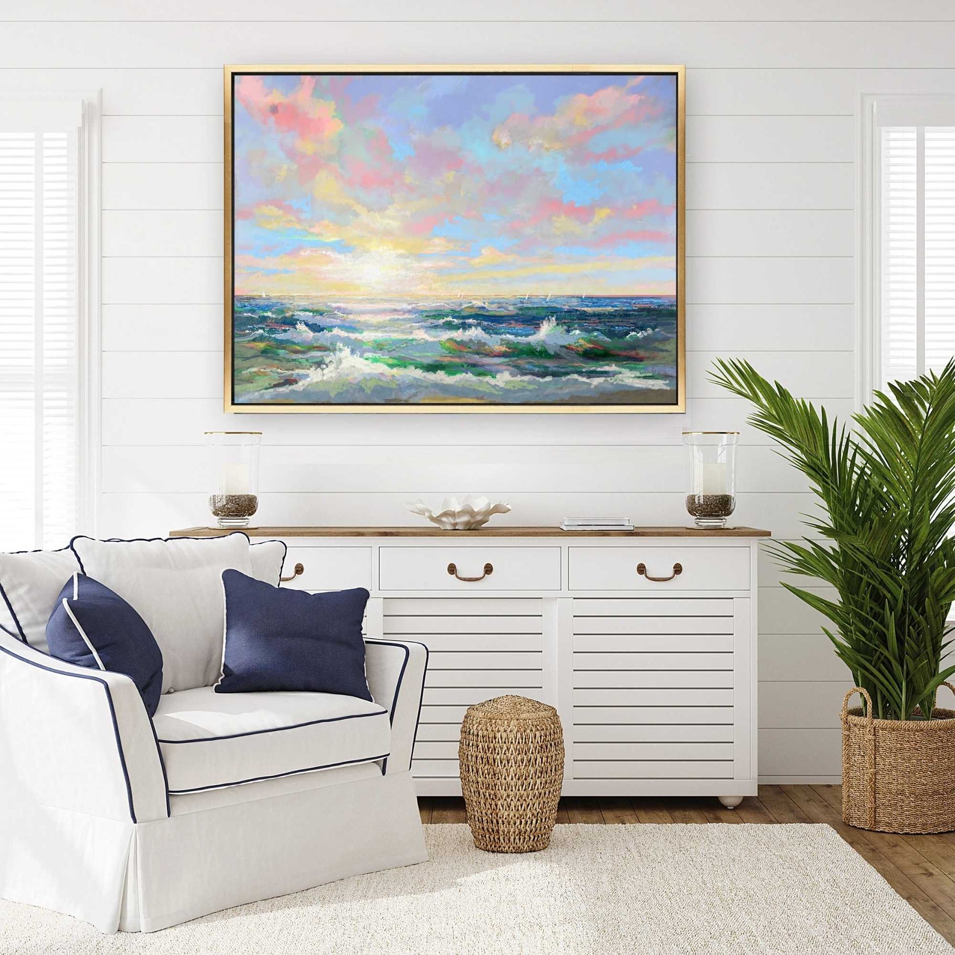 Living room with a white sofa, decorative pillows, a sideboard, and a large framed painting of a colorful sky and ocean.