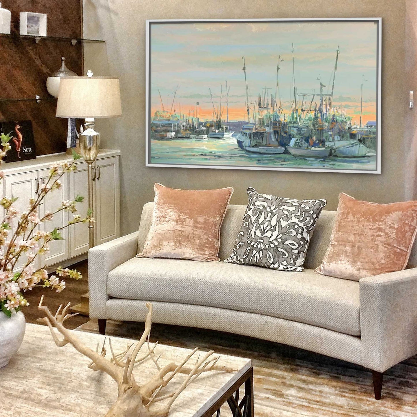 Living room with a beige sofa, decorative pillows, and a large painting of a harbor scene.