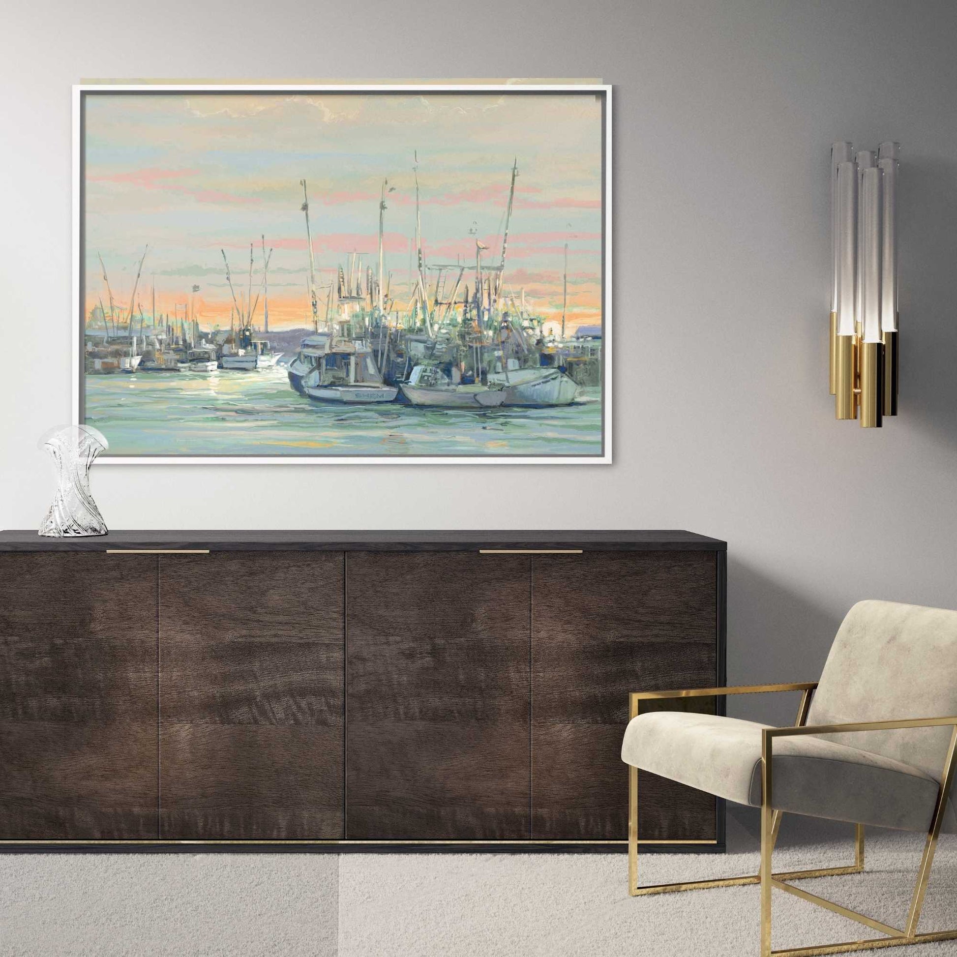 Modern interior with a large framed painting of a harbor scene, dark wooden cabinet, and beige chair.
